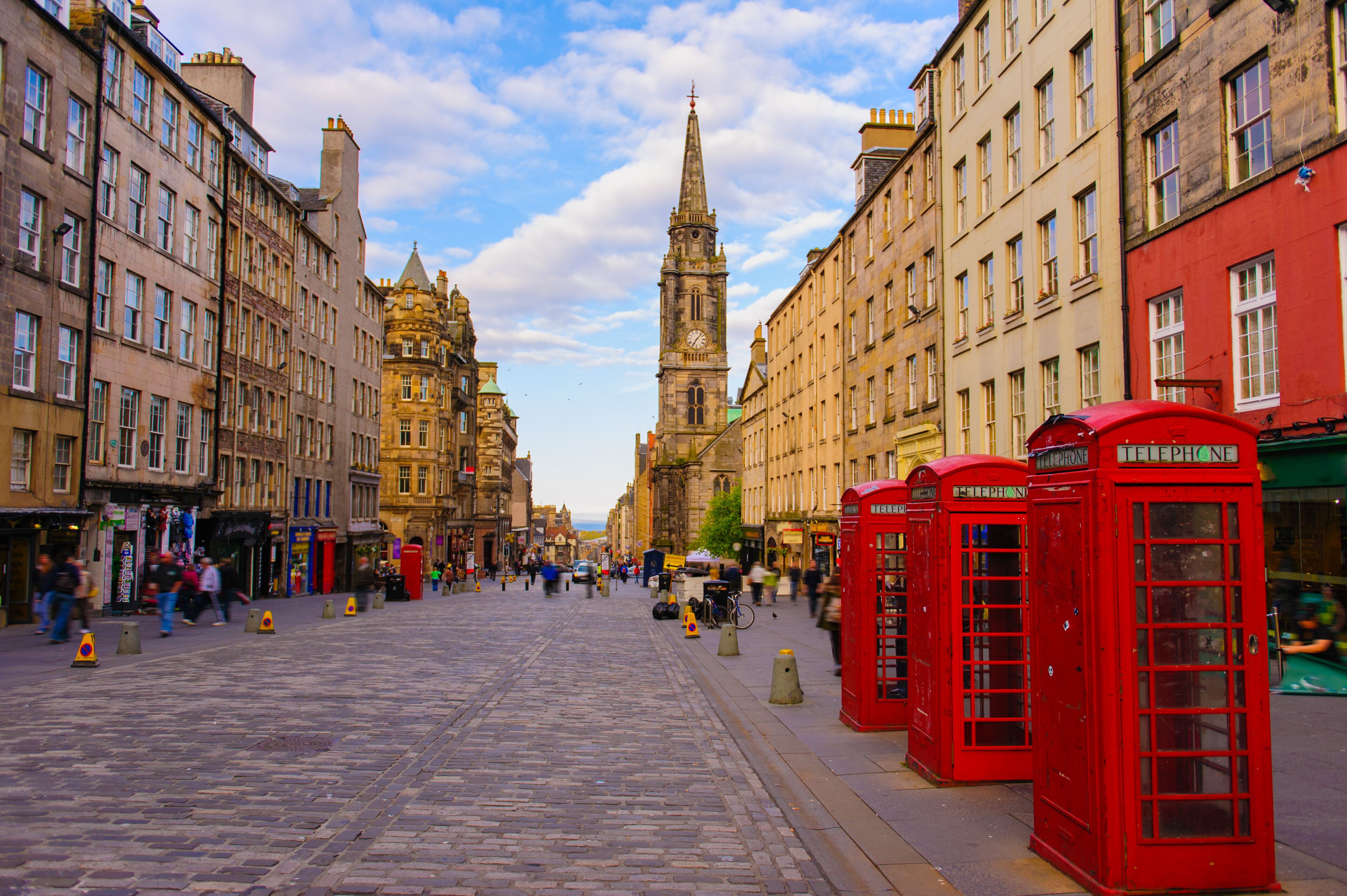 A cobblestone street lined with historic buildings and a prominent clock tower.