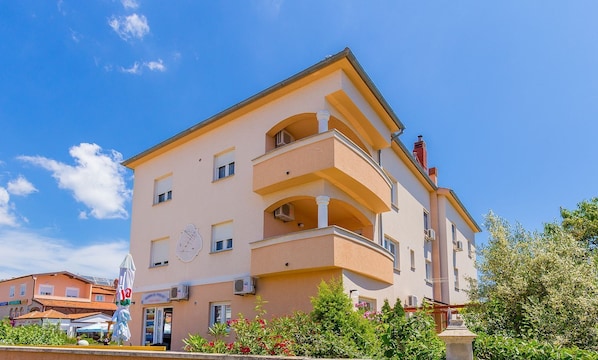 A multi-story building with balconies, a clock, and air conditioning units.