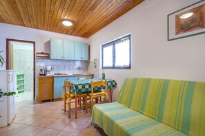 Una cocina compacta con zona de comedor, un sofá y una ventana.