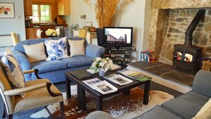 A cozy living room with a sofa, coffee table, and fireplace. - Luxury 5-star single-storey cottage for two near the Cornish coast (Helston)