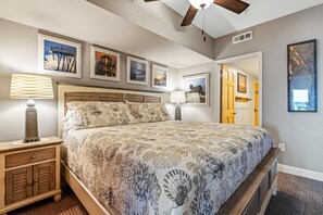 A bedroom with a bed, nightstands, and wall art. - 2 Bedroom Oceanfront 2 Bath K, Q & Sleep Sofa Large kitchen (Kill Devil Hills, NC 27948)