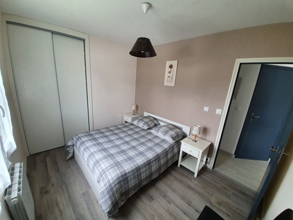 A bedroom with a bed, bedside tables, a wardrobe, a door, and a ceiling light.