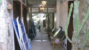 Une porte surmontée d’un luminaire en forme d’étoile, des chaises en osier et un cactus.