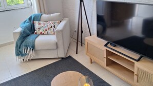 A modern living room with a sofa, a TV, a lamp, and a candle on a table.