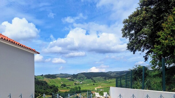 A gated property with a pool, a view of rolling hills, and a clear sky.
