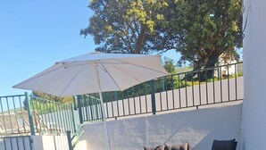 A patio with stone flooring, outdoor furniture, and a large umbrella.