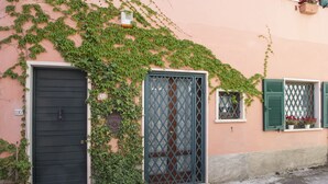 A building with a black door, a window with a lattice design, and a small window with green shutters. - LUMIERE LIFE, cozy and bright living room in Castelnuovo Magra  (Castelnuovo Magra)