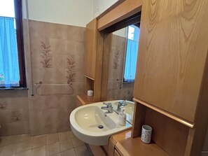 Un baño con lavamanos, espejo y cabina de ducha.