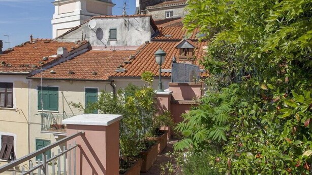 A rooftop terrace with a tiled floor, a metal railing, and a view of a historic building with a bell tower. - LUMIERE LIFE, cozy and bright living room in Castelnuovo Magra  (Castelnuovo Magra)