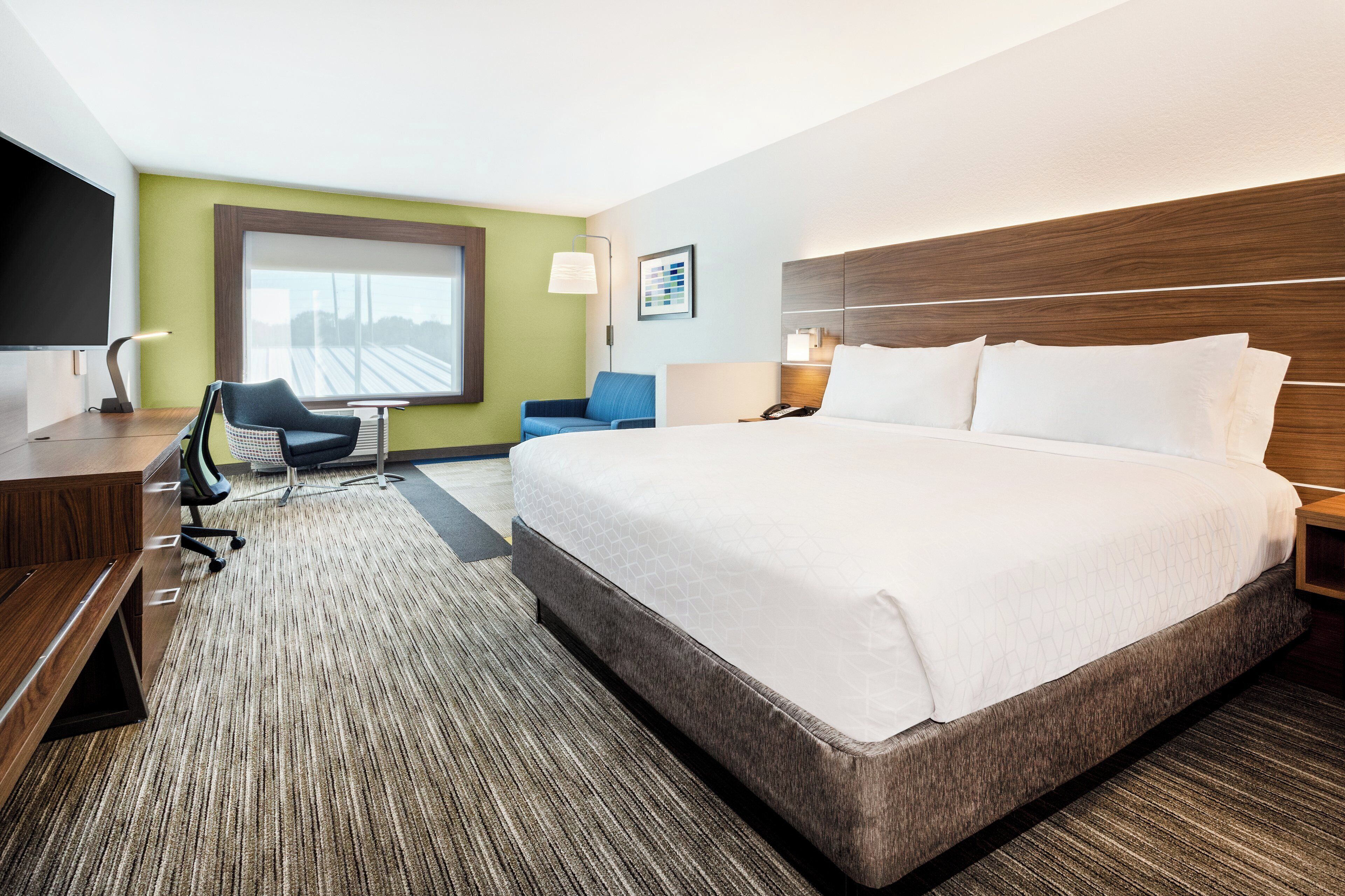 Une chambre d’hôtel avec un grand lit, un bureau avec une chaise, une petite table et un téléviseur.