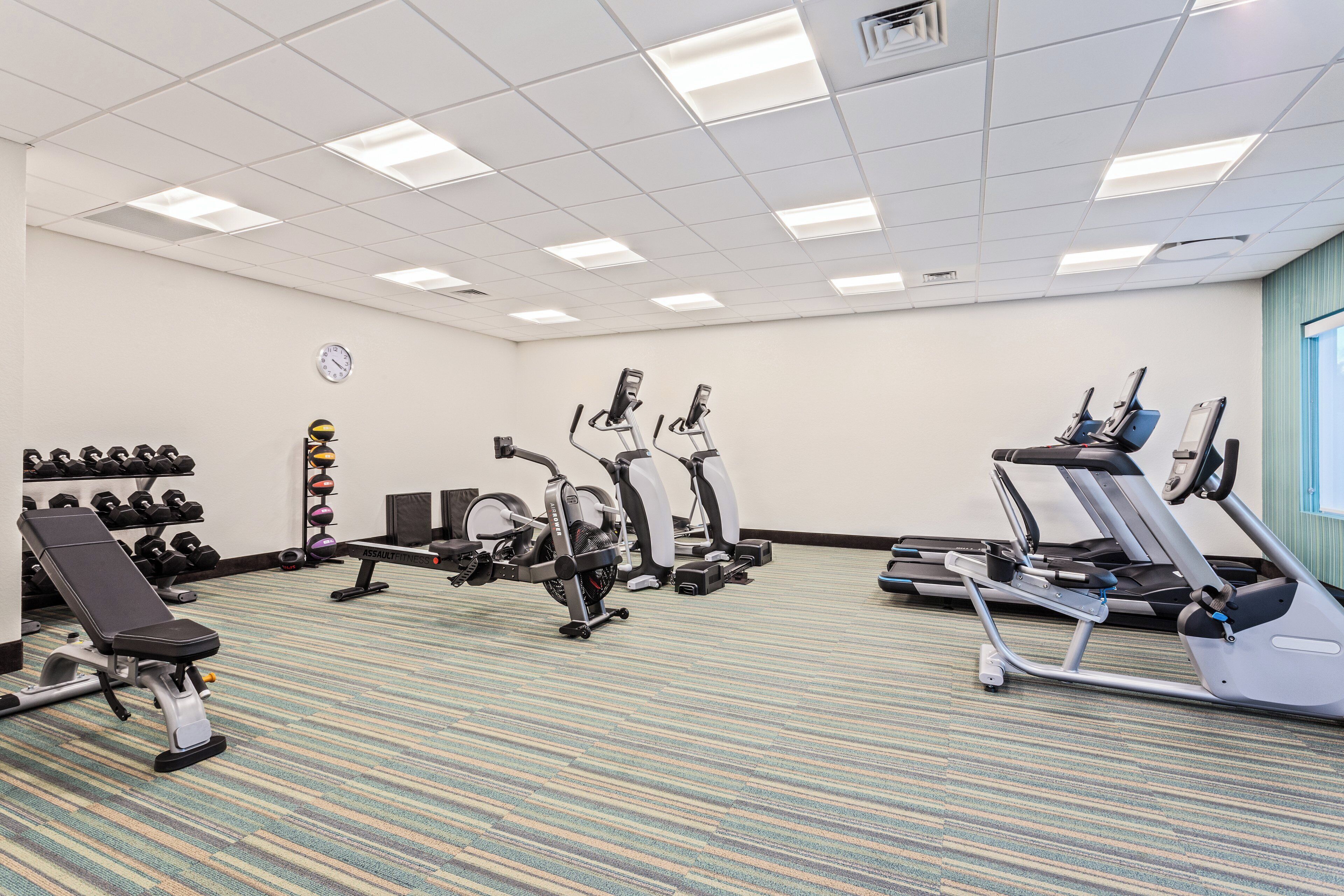 A gym with various exercise equipment, including treadmills, an elliptical, and free weights.