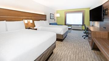 A hotel room with two beds, a desk, a chair, a TV, and a window.