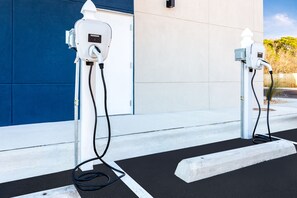 Two electric vehicle charging stations with cables connected to them, set against a building with a blue and white facade. - Holiday Inn Express & Suites Niceville - Eglin Area by IHG (Niceville)