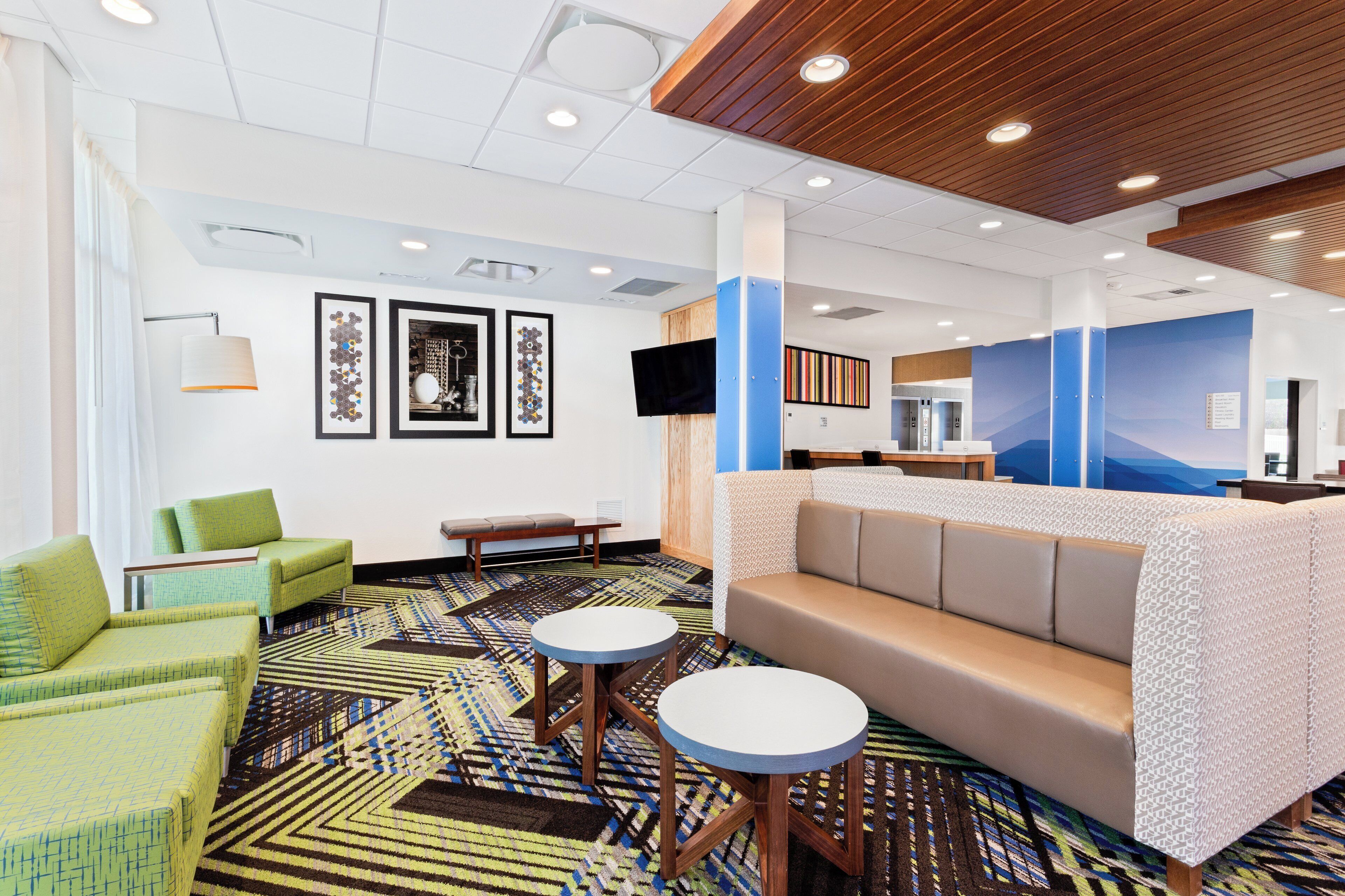 A hotel lobby with a reception desk, seating area, and artwork on the walls.