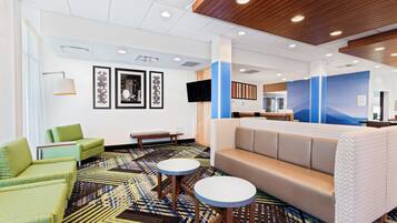 A hotel lobby with a reception desk, seating area, and artwork on the walls.