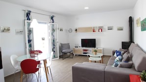 Een moderne woonkamer met een bank, televisie en een eetgedeelte met stoelen en een tafel.
