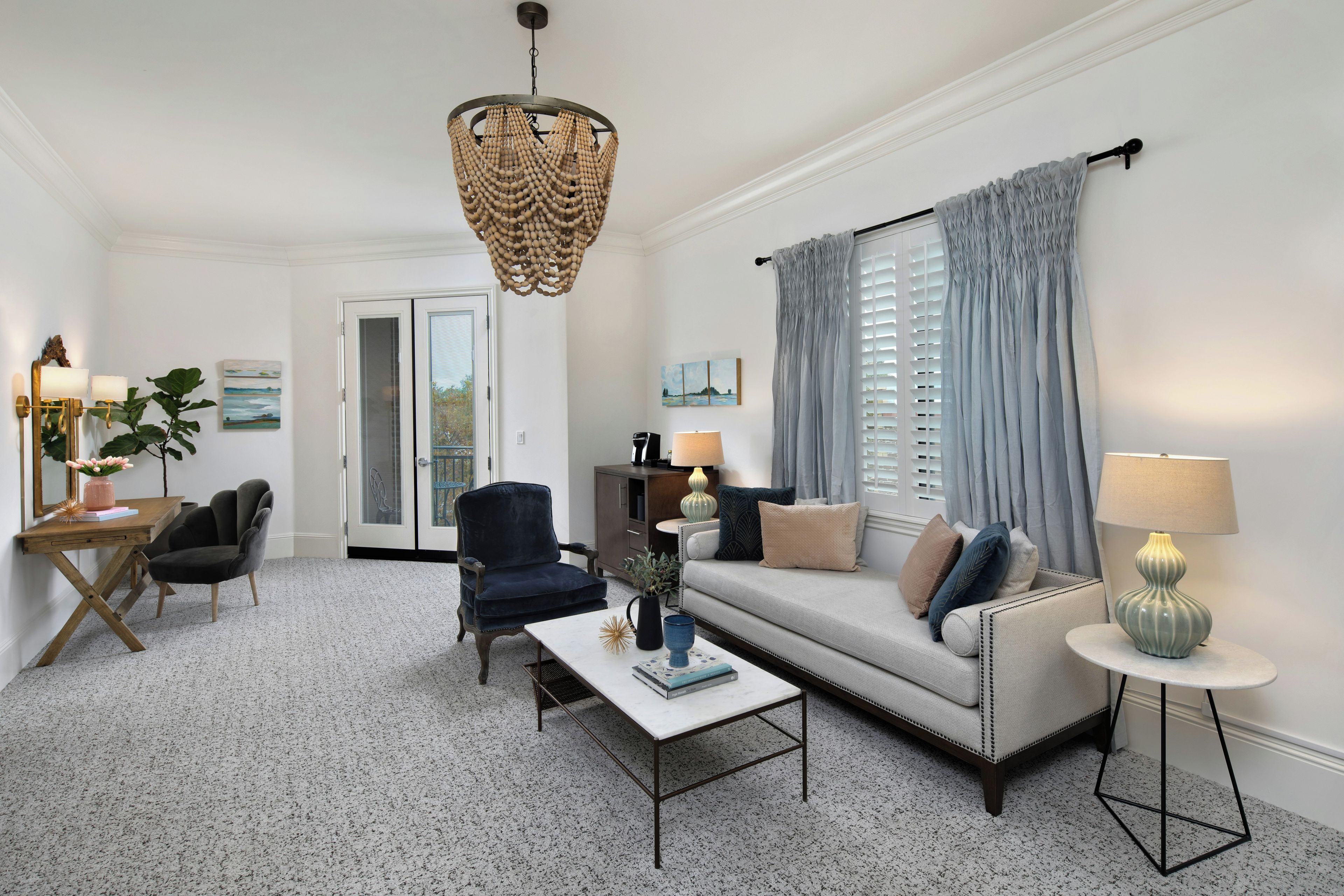 A modern living room with a sofa, armchairs, a coffee table, and a chandelier.