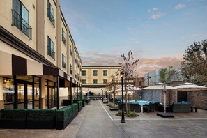 A courtyard with outdoor seating, a pool, and a building with multiple windows.
