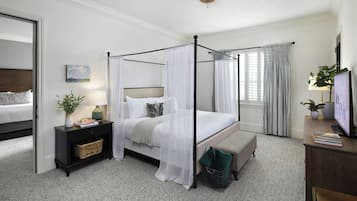 Uma cama de dossel com cortina, uma mesa de cabeceira com abajur, uma planta na cabeceira e vista para um quarto com cama e cortinas.