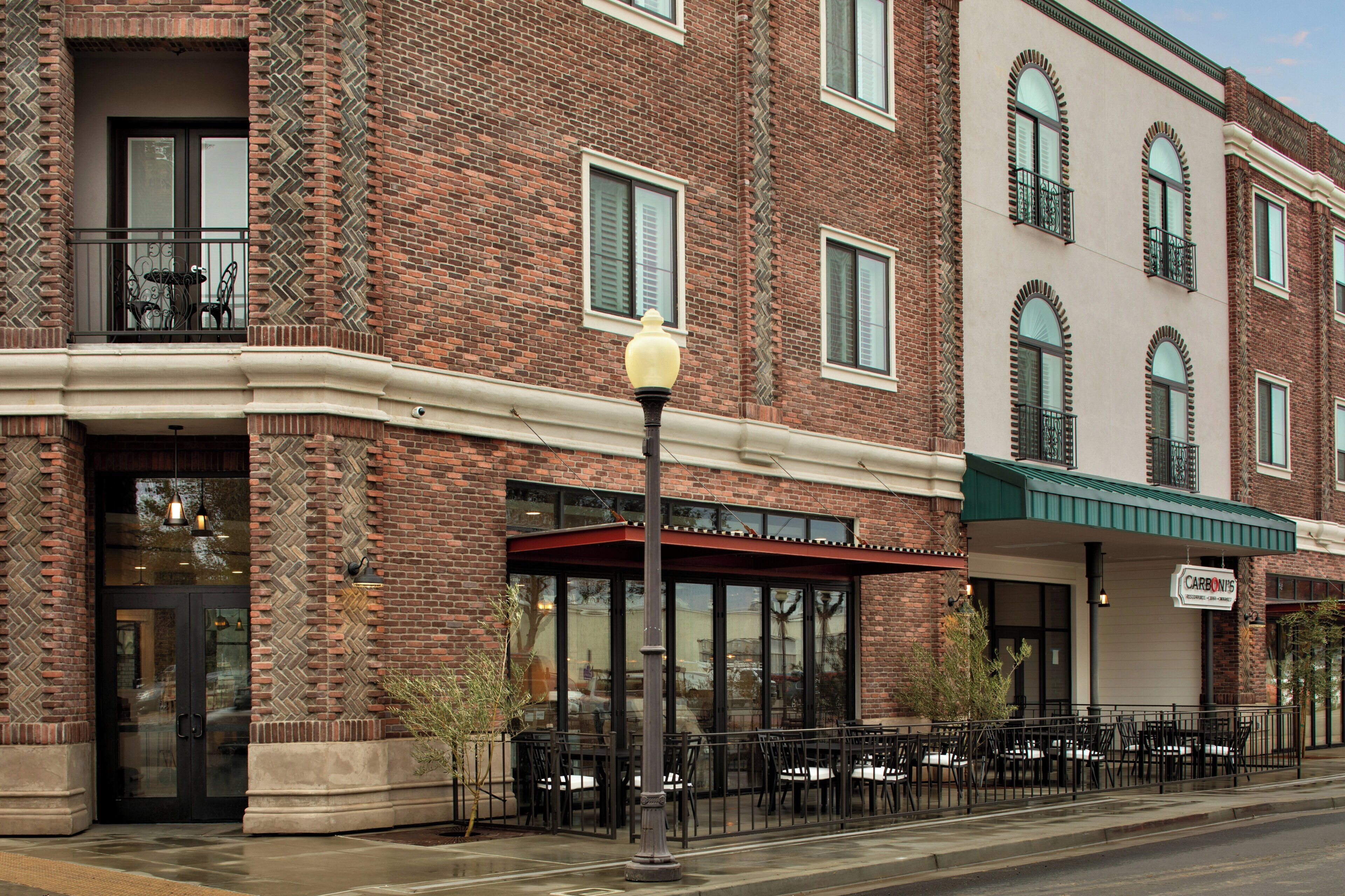 A brick building with a corner entrance, outdoor seating area, and a sign for 'CARBON'S'.