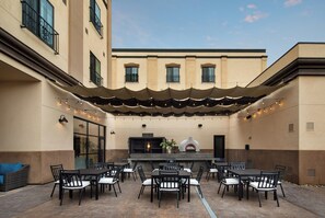 An outdoor patio with a dining area, tables, chairs, and a pizza oven. - Hotel Winters (Winters)