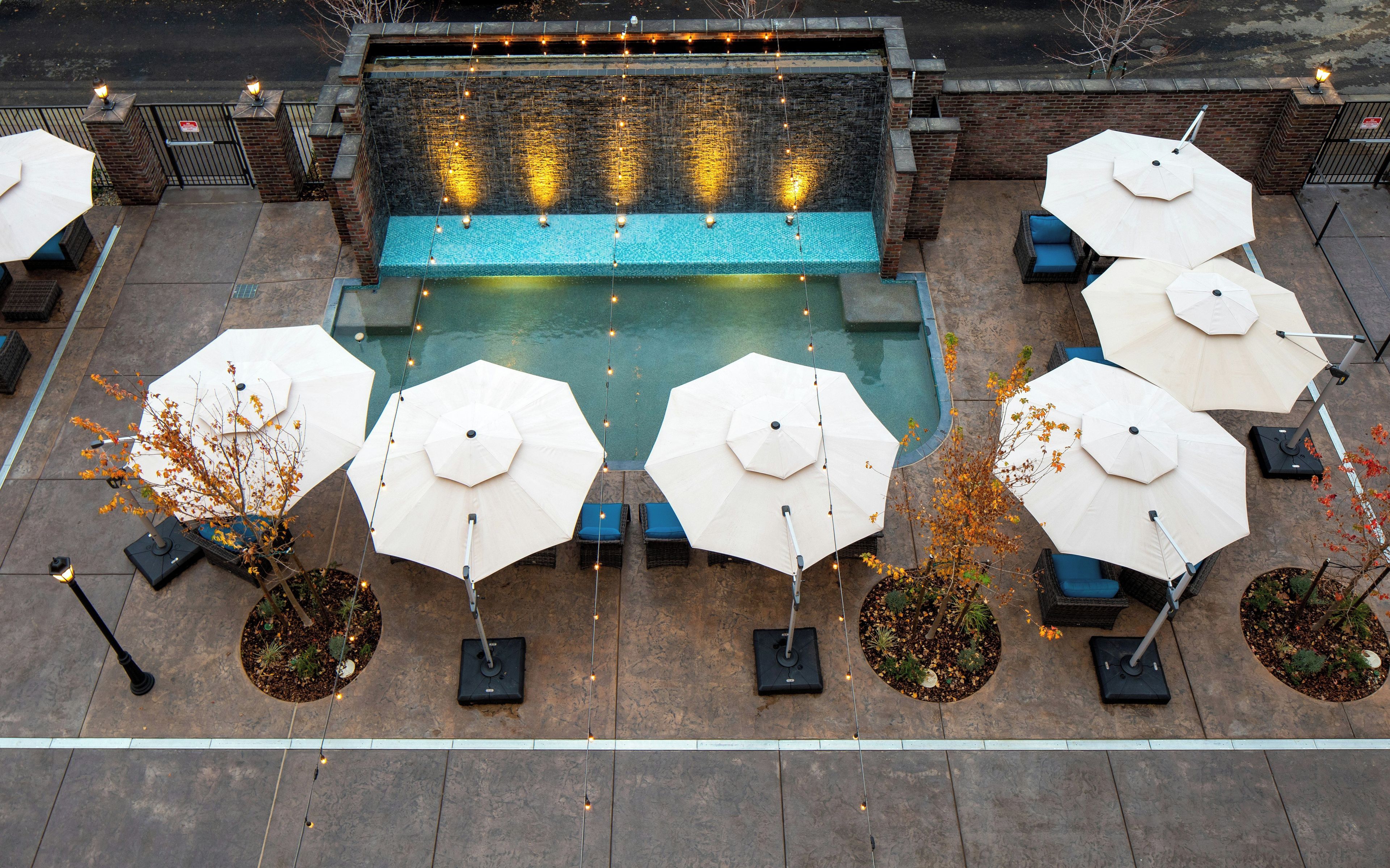 Un espace piscine sur le toit, doté de plusieurs parasols et de nombreux sièges.