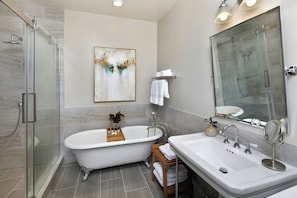 A modern bathroom with a glass-enclosed shower, a freestanding bathtub, and a vanity with a large mirror. - Hotel Winters (Winters)