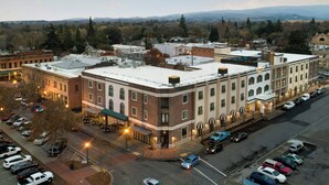 A multi-story building with a flat roof, a parking lot, and a street view. - Hotel Winters (Winters)