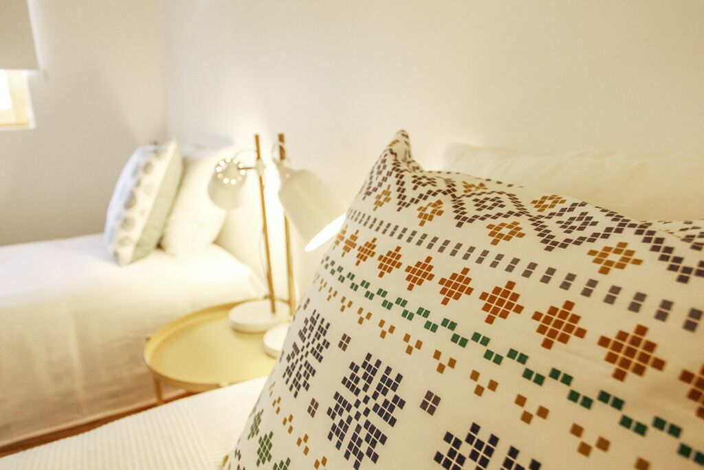 Une pièce chaleureuse avec un canapé blanc, un coussin à motifs et une petite table d’appoint ronde.