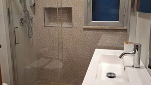 Een badkamer met een douche, toilet en wastafel.