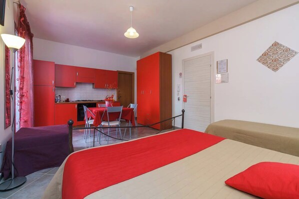 A room with a bed, a dining table, and a kitchenette.