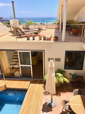 A rooftop pool area with a view of the ocean, a covered seating area, and potted plants. - Villa with private pool, glas fibre internet, close to ocean, protected patio (Costa Calma)