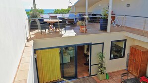 Un edificio a due piani con un balcone, posti a sedere all'aperto e vista sul mare.