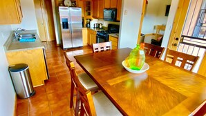 Una cocina amplia con armarios de madera, un refrigerador de acero inoxidable y un comedor con mesa y sillas de madera.