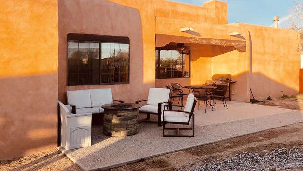 Un patio con mobiliario exterior, una chimenea y una parrilla.