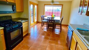Una cocina con estufa, horno y mesa de comedor con sillas.
