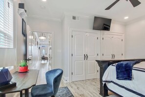 A hotel room with a bed, a desk with a computer, a chair, a TV, and a wardrobe.