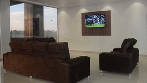 Una sala de estar moderna con un ventanal grande, un televisor de pantalla plana montado en la pared y dos sofás marrón oscuro.