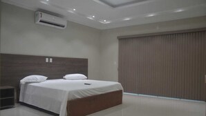 Un dormitorio moderno con una cama grande, un equipo de aire acondicionado y una puerta corrediza.
