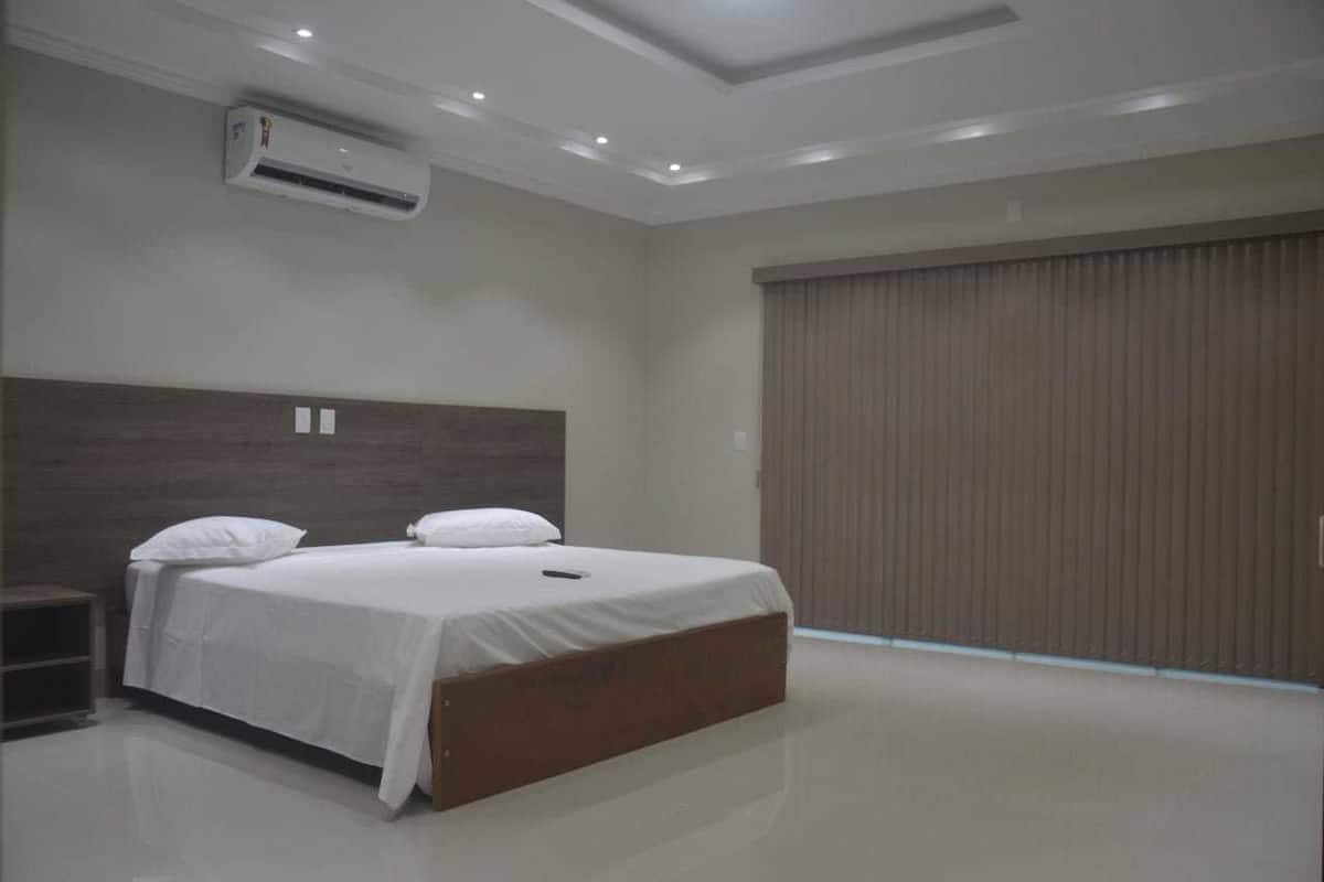 Un dormitorio moderno con una cama grande, un equipo de aire acondicionado y una puerta corrediza.