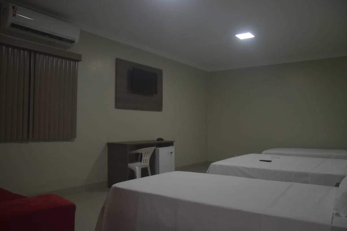 Una habitación de hotel con dos camas, un escritorio, una silla y un aire acondicionado.