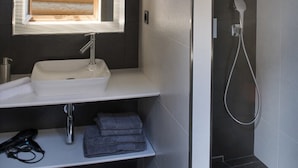 A modern bathroom with a wooden-framed mirror, a white sink, and a shower. - OVEN SUITE PREMIUM BLACK & WHITE (Les Angles)