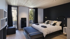 A modern bedroom with a large bed, a bench, a desk, and a chair. - OVEN SUITE PREMIUM BLACK & WHITE (Les Angles)