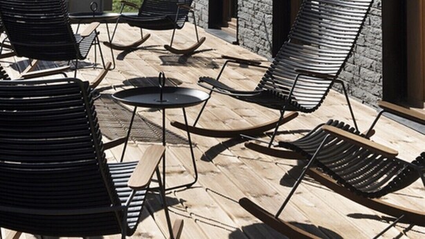 A terrace with wooden flooring, black lounge chairs, and a stone building with large windows. - OVEN SUITE PREMIUM BLACK & WHITE (Les Angles)