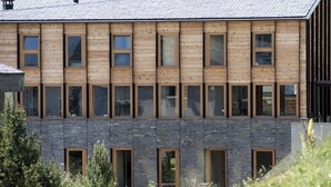 A modern building with a wooden facade and stone base, featuring multiple windows and doors. - OVEN SUITE PREMIUM BLACK & WHITE (Les Angles)