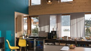 Cocina moderna con comedor, que cuenta con un ventanal grande, techo de madera y una cafetera.