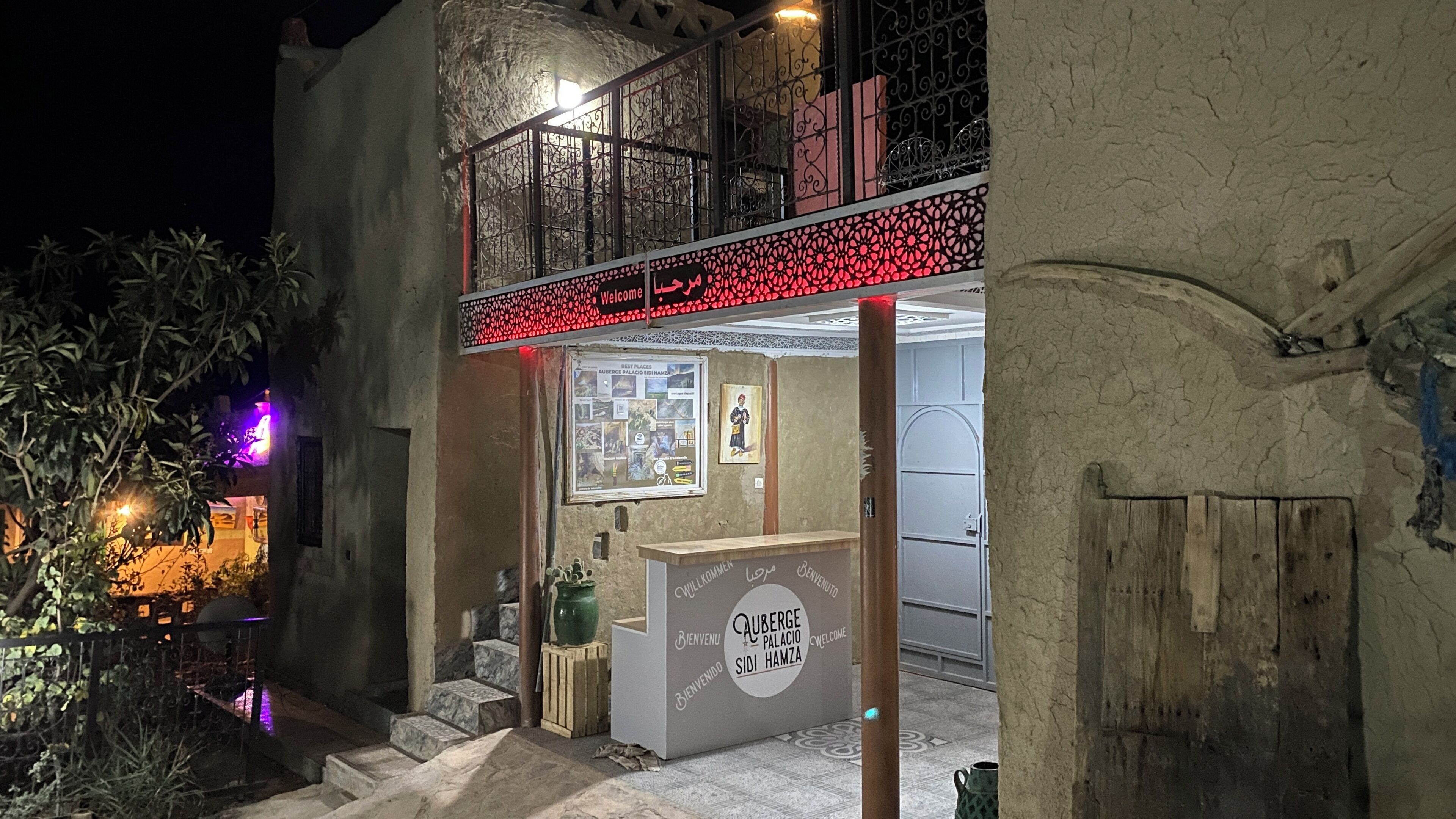 Un edificio con balcón, un cartel de bienvenida y una exposición de arte local.