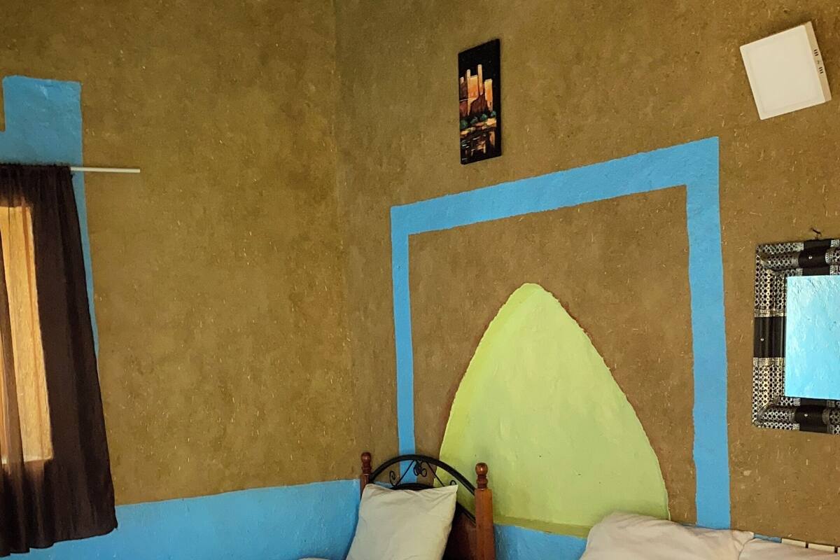 Een kamer met twee bedden, een houten plafond en een muur met een lijst eromheen.