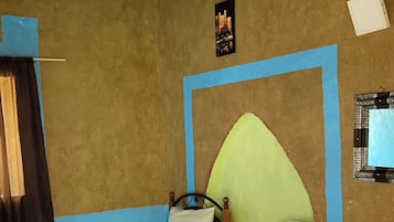 A room with two beds, a wooden ceiling, and a wall with a framed picture.