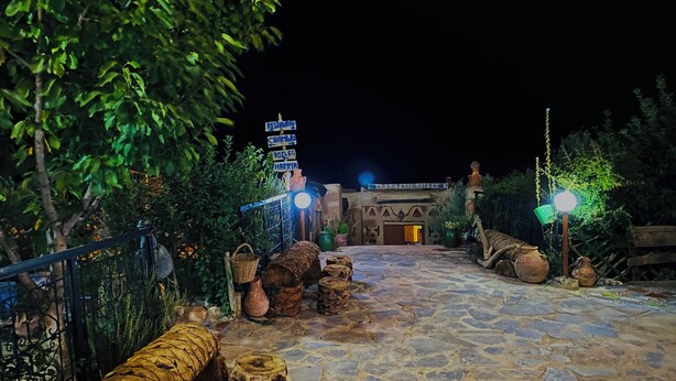 Un chemin de pierre mène à un bâtiment rustique sur lequel on peut voir une enseigne indiquant la présence d’un restaurant.